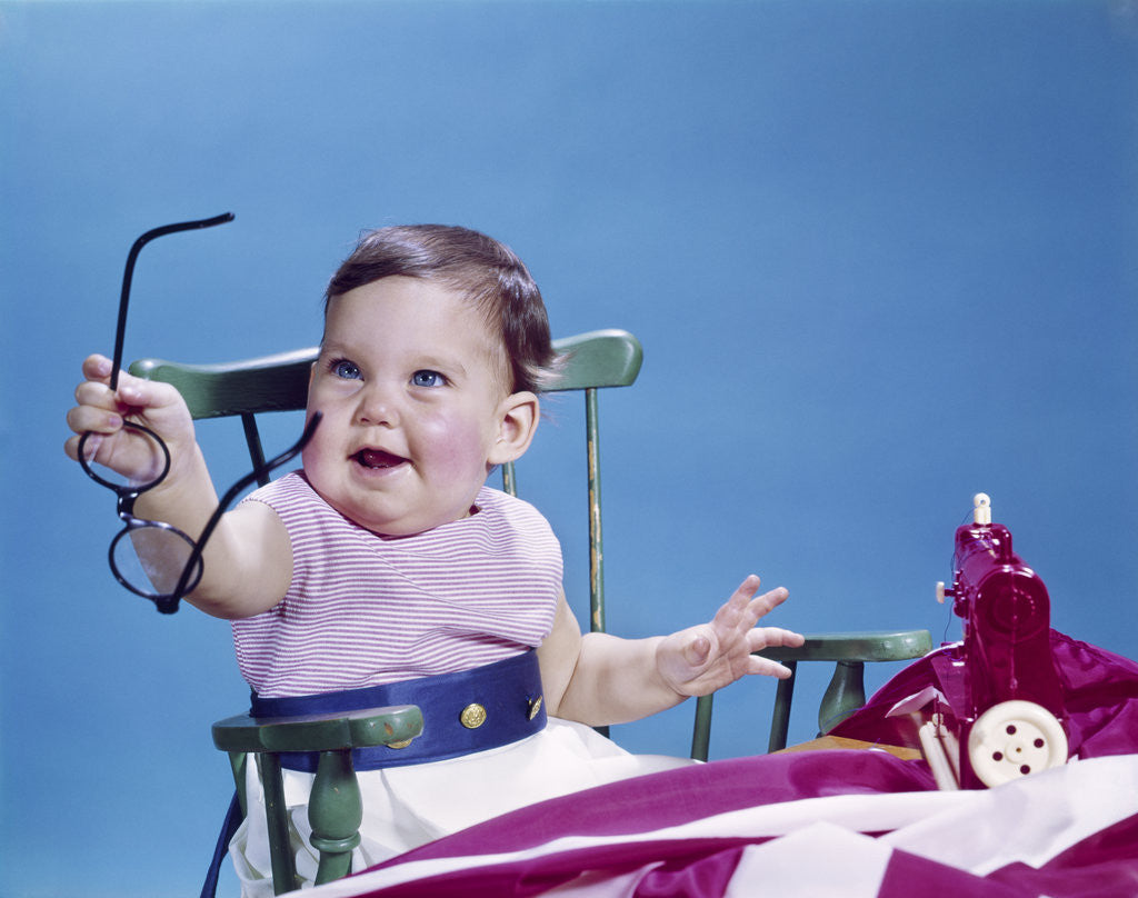 Detail of 1960s smiling baby holding eyeglasses by Corbis