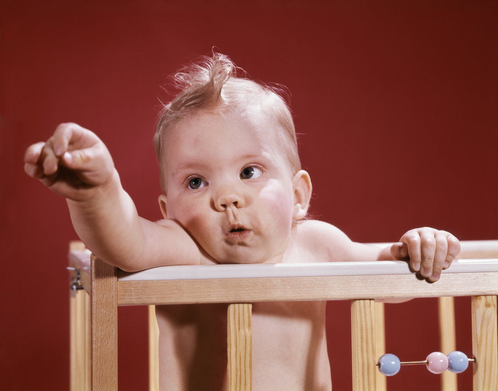 Detail of 1960s baby reaching out from crib by Anonymous