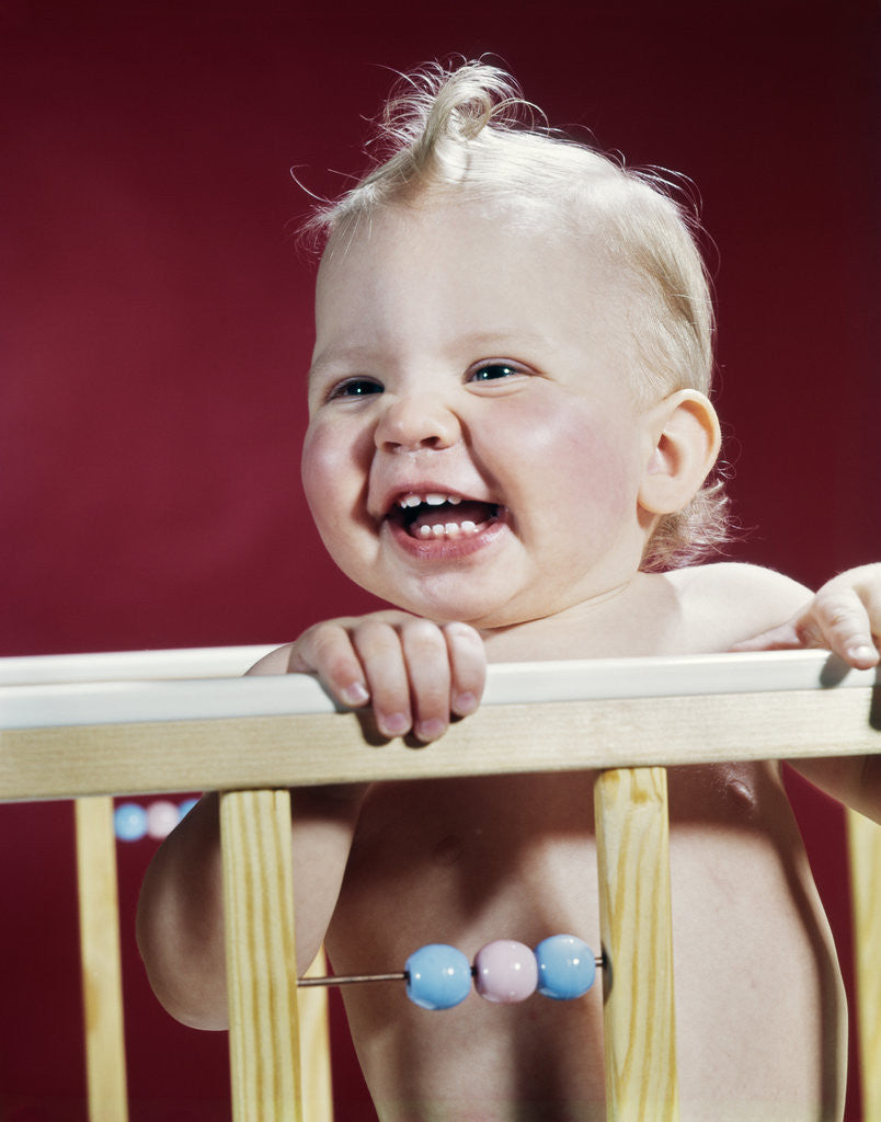 Detail of 1960s laughing blond baby in crib or playpen by Anonymous