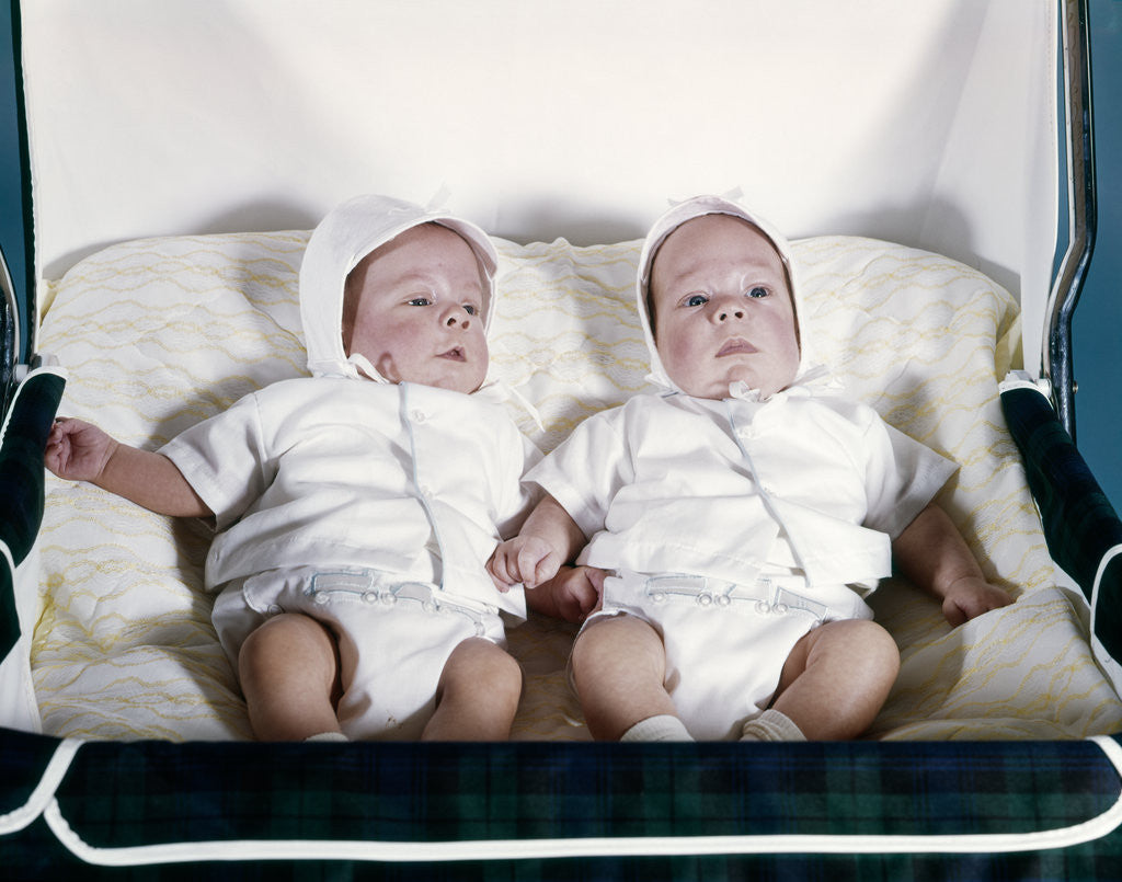 Detail of 1950s 1960s twin boys dressed in white lying in stroller side by side by Anonymous