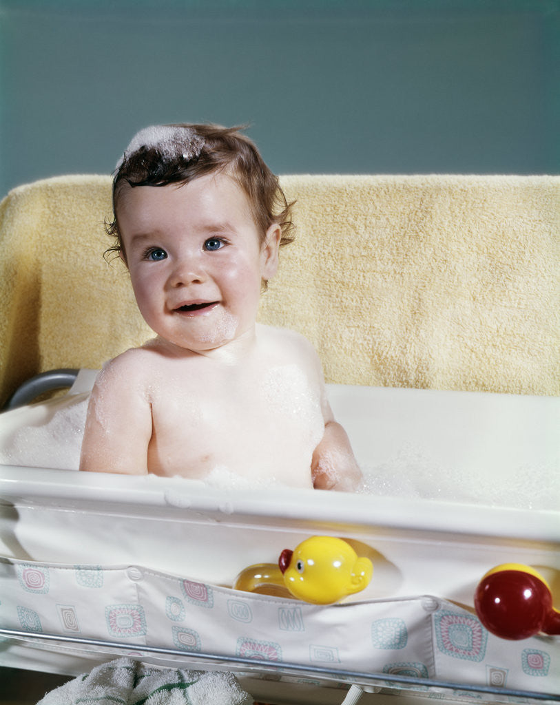 Detail of 1960s smiling baby in bath looking at camera by Anonymous