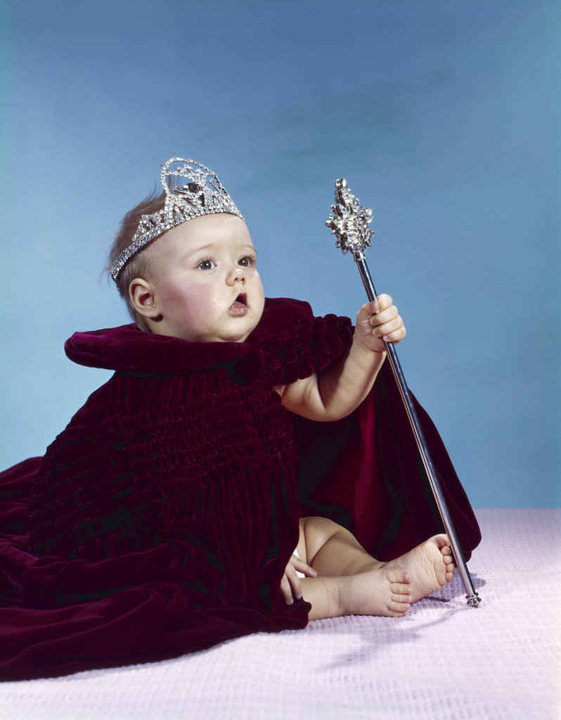 Detail of 1960s baby dressed as royal queen in a velvet robe cloak cape rhinestone tiara crown and scepter wand by Anonymous