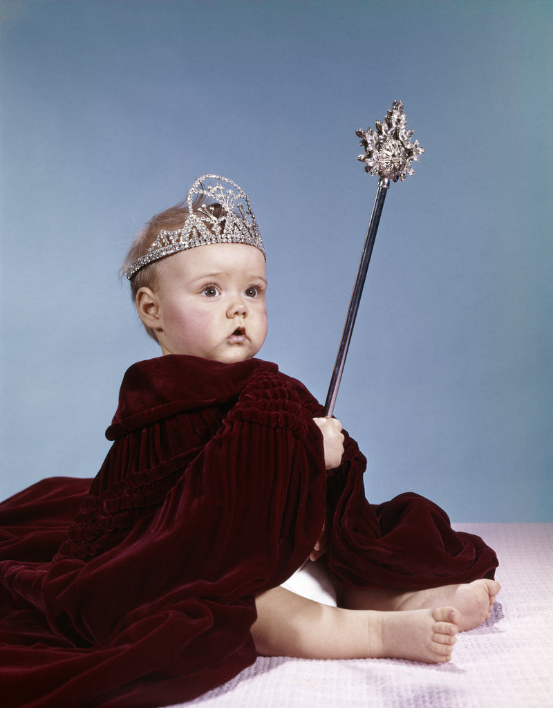 Detail of 1960s baby girl wearing rhinestone tiara and red velvet cloak holding scepter by Anonymous