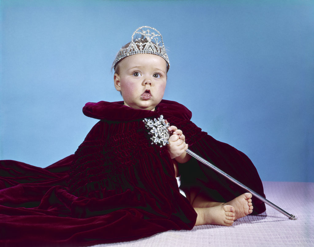 Detail of 1960s baby dressed as royal queen in red velvet robe cloak cape rhinestone tiara crown and scepter wand by Anonymous