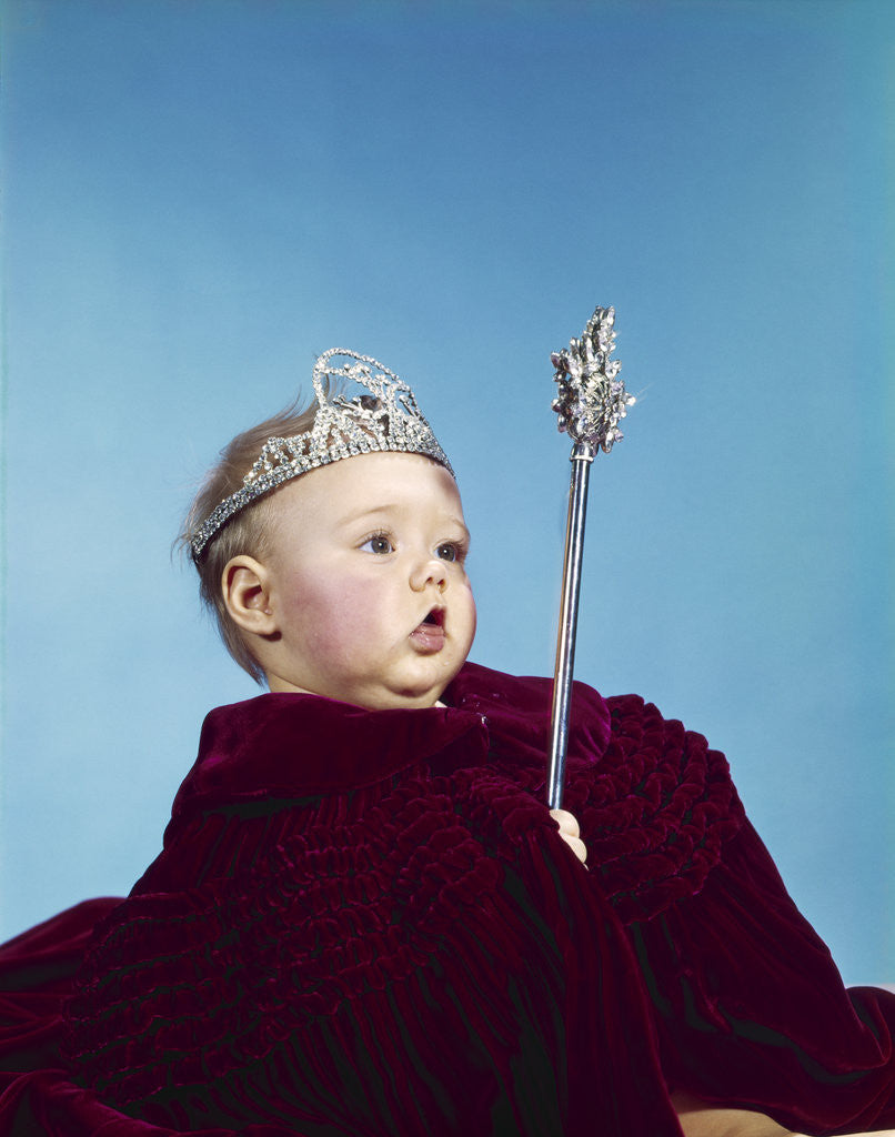 Detail of 1960s baby dressed as royal queen in a velvet robe cloak cape rhinestone tiara crown and scepter wand by Anonymous