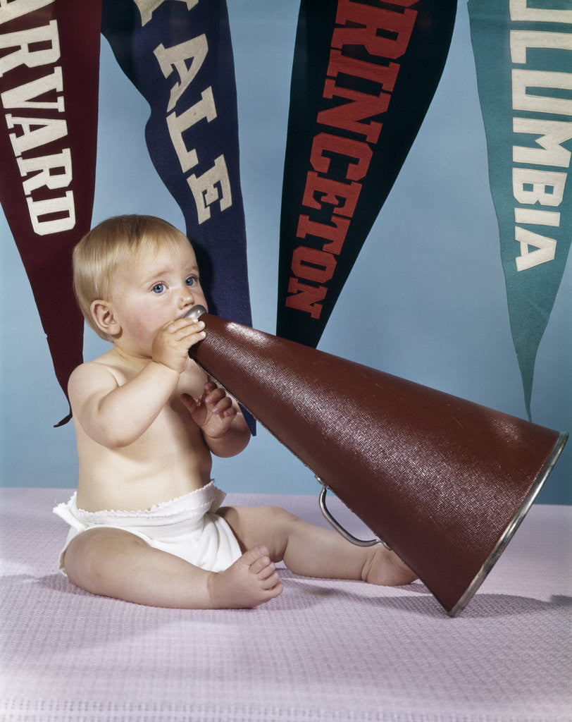 Detail of 1960s baby shouting into cheerleader megaphone college pennants in background by Anonymous