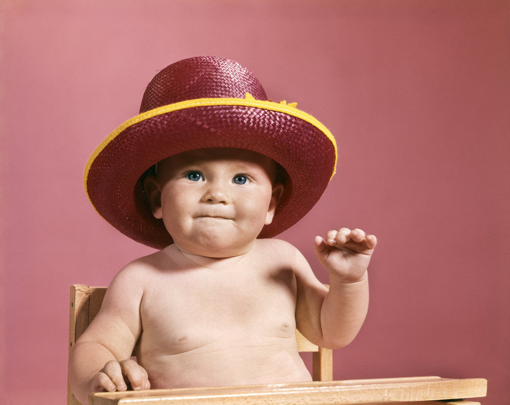 Detail of 1960s baby making face wearing red straw hat by Anonymous