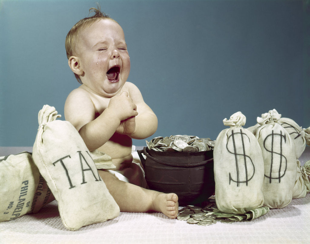 Detail of 1960s baby crying laughing mouth wide open with pot of coins and bags of money including bag labeled tax by Corbis