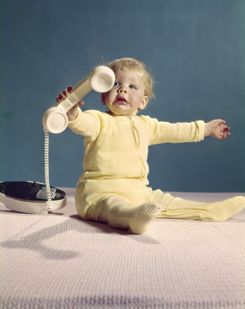 Detail of 1960s baby holding telephone head set by Anonymous