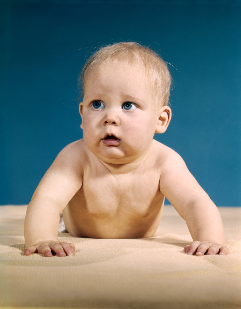 Detail of 1960s baby big blue eyes raised up on arms looking to side by Anonymous