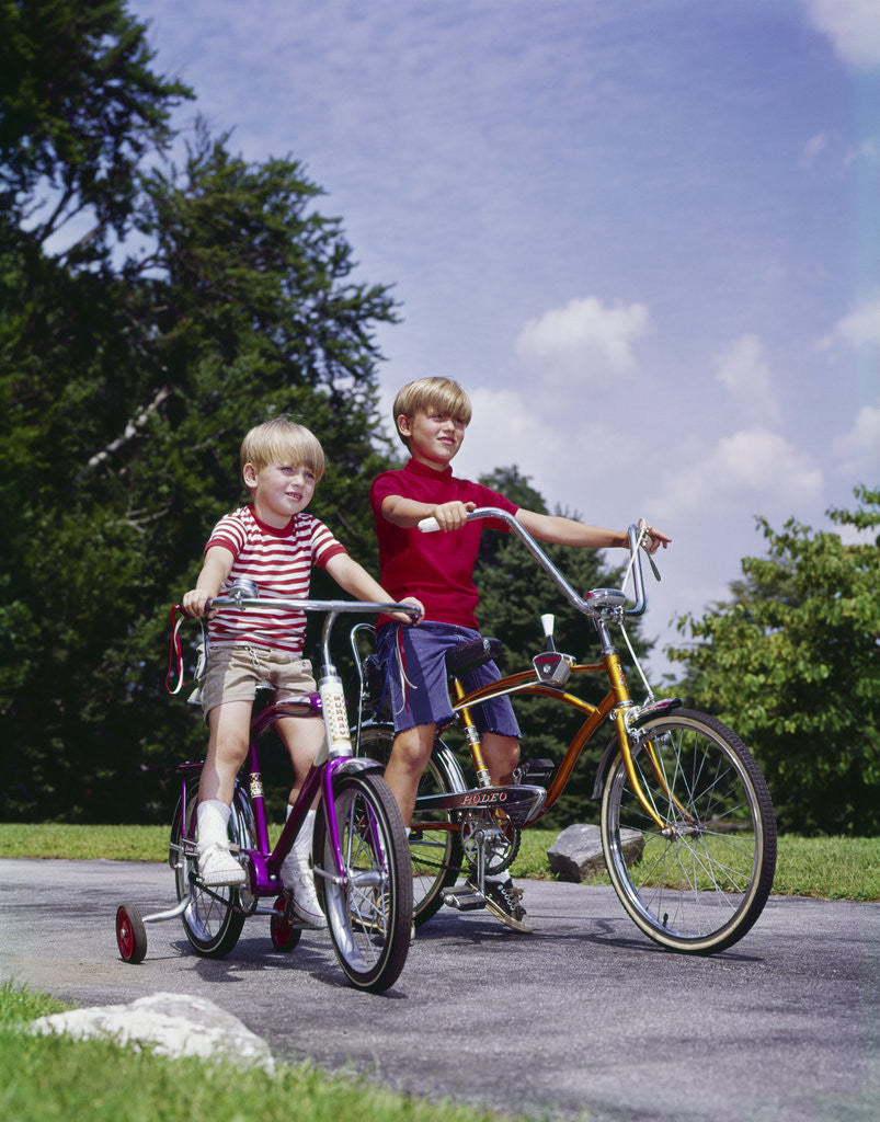 Detail of 1970s 1960s two boys riding bikes in park summer by Anonymous