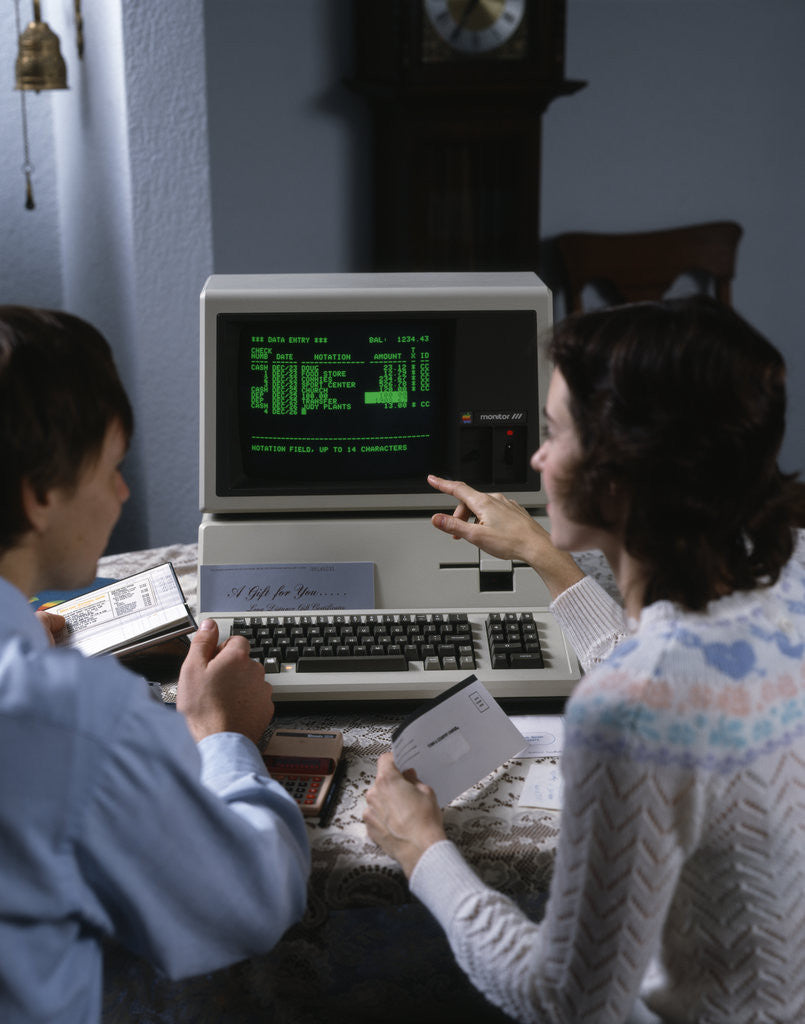 Detail of 1980s couple working at apple iii 3 home computer paying bills by Anonymous