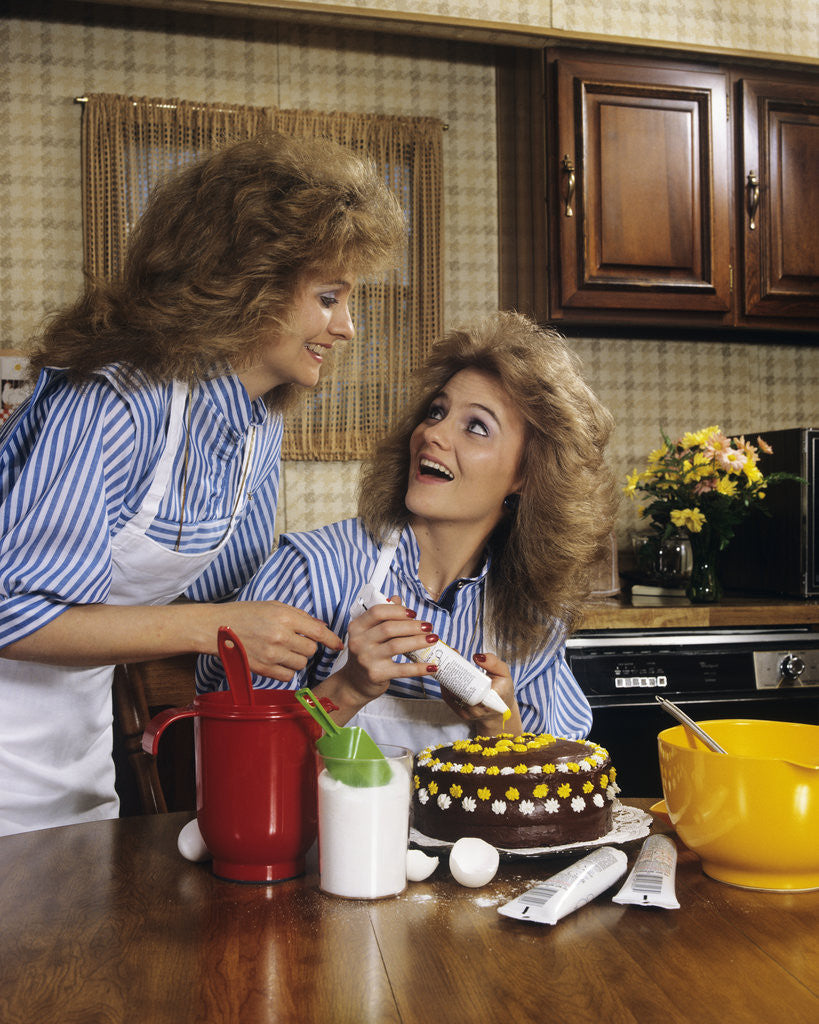 Detail of 1970s mother daughter dressed alike decorating cake by Corbis