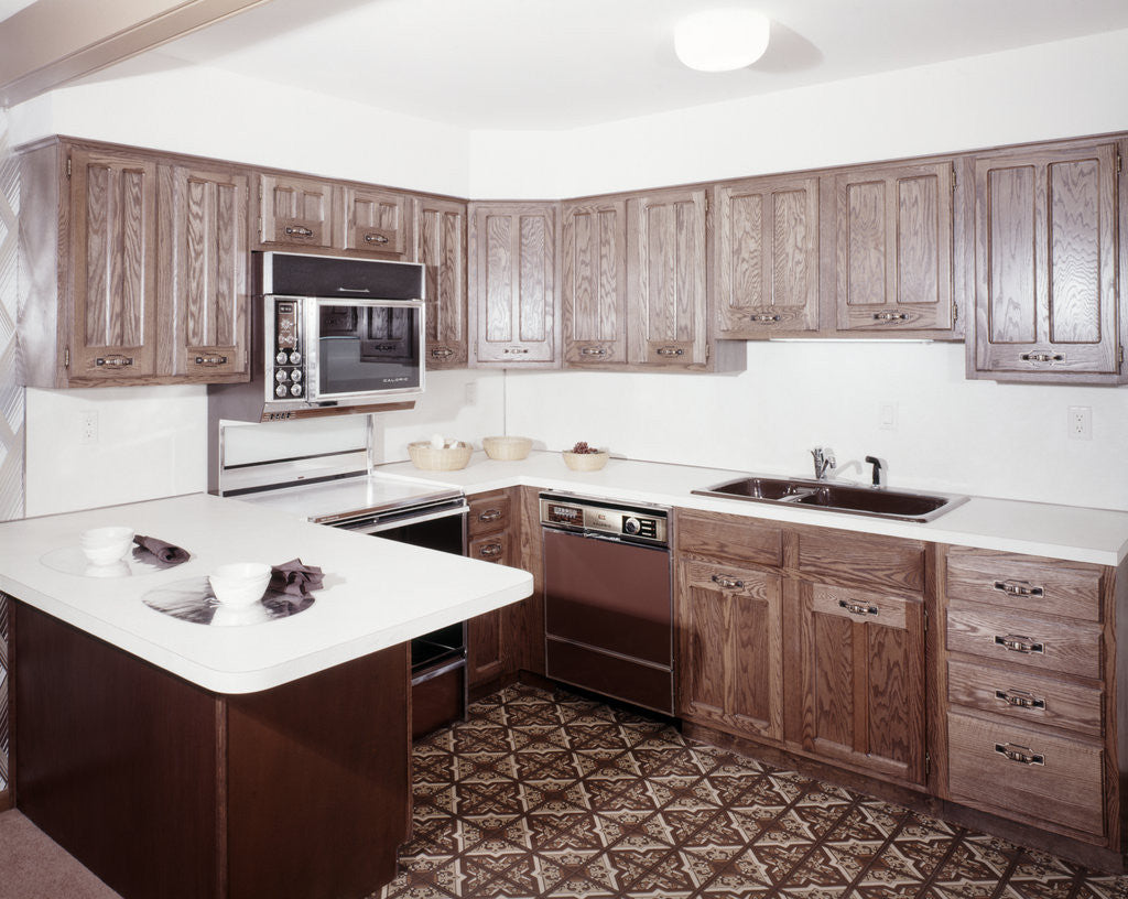 Detail of 1970s kitchen with dark wooden cabinets and a microwave oven over the stove by Anonymous