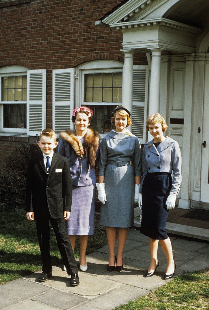 1950s mother with teenage girls & younger son dressed up posing in front of house by Corbis