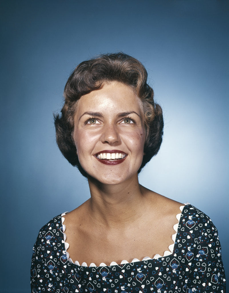 Detail of 1960s smiling brunette woman in print dress looking up by Anonymous