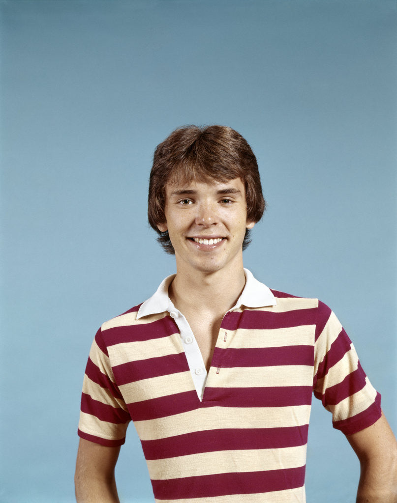 Detail of 1970s portrait of smiling teenage boy wearing striped rugby shirt looking at camera by Anonymous