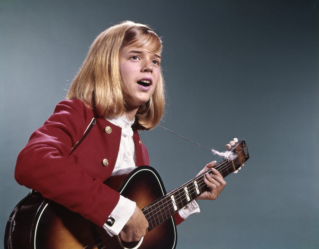 Detail of 1960s blond teenaged girl singing and playing acoustic guitar by Anonymous