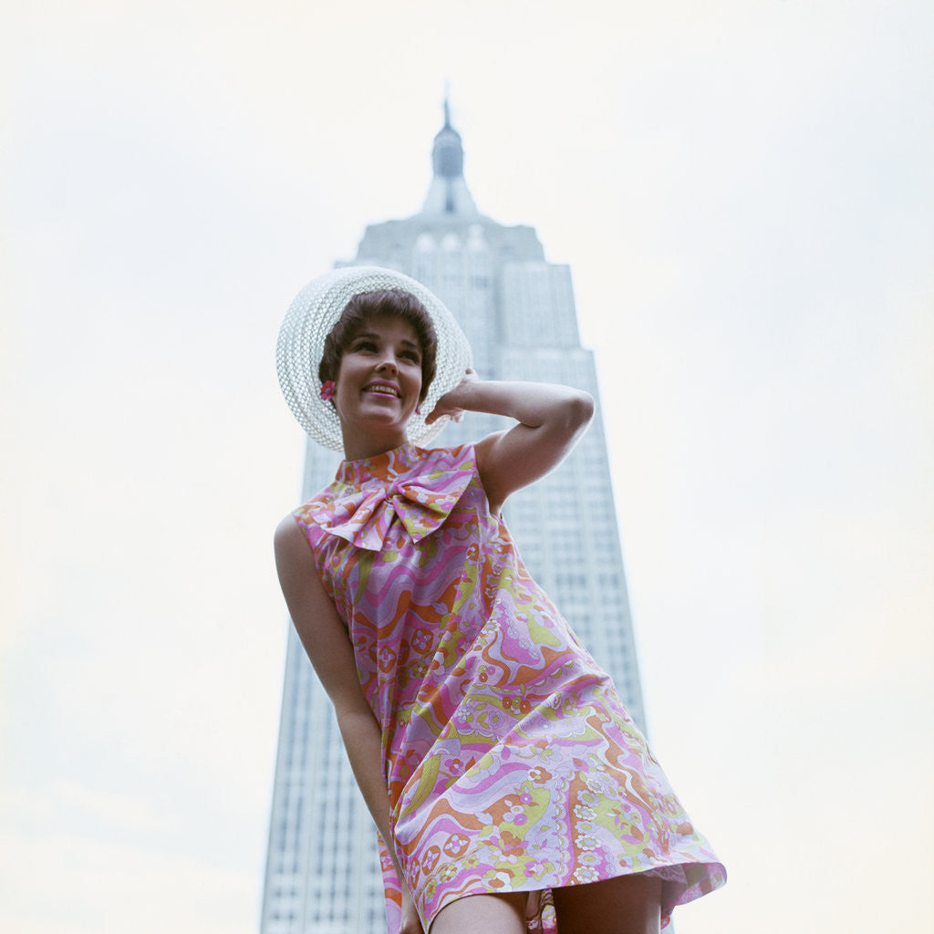 Detail of 1960s young woman print miniskirt dress summer hat in front empire state building new york city by Anonymous