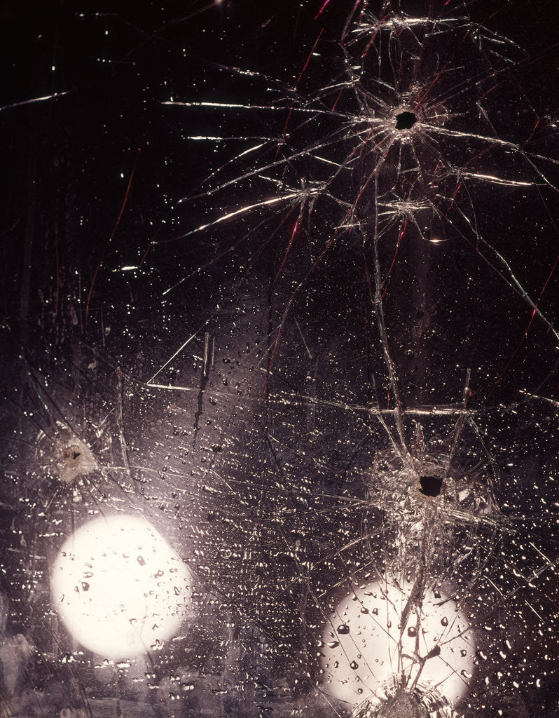 Detail of 1970s bullet holes and raindrops on shattered glass windshield by Anonymous