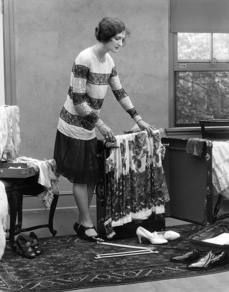 Detail of 1920s woman packing clothes for travel by Corbis