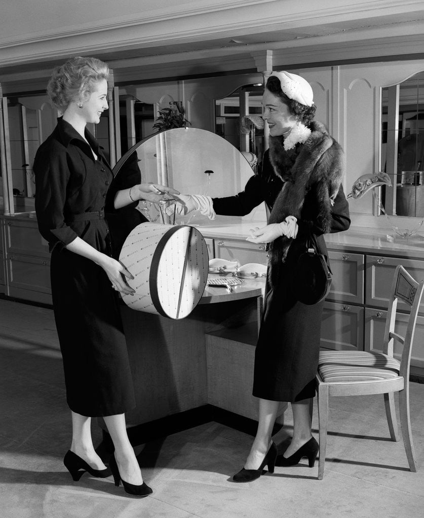 Detail of 1950s woman in hat stole & gloves taking hatbox from saleswoman by Corbis