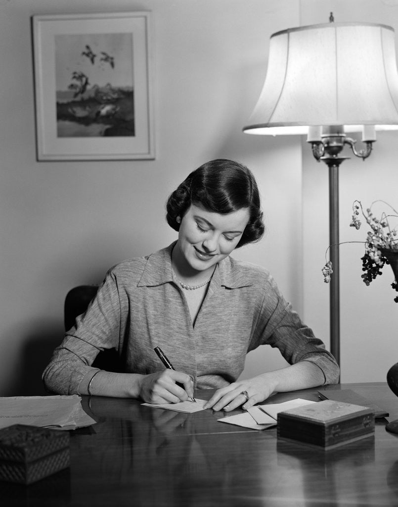 Detail of 1940s 1950s woman sitting at desk writing letters doing correspondence by Corbis