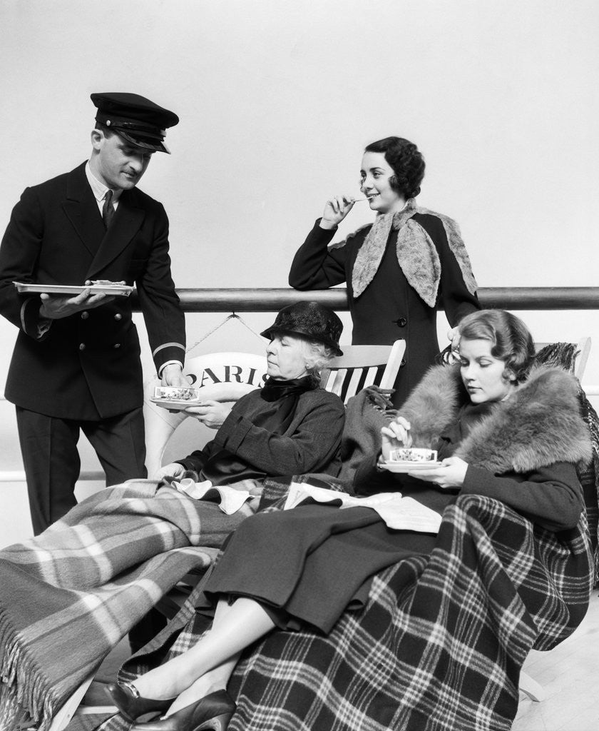 Detail of 1930s 1920s three women being served tea by a steward on board an ocean liner crossing the atlantic ocean by Corbis