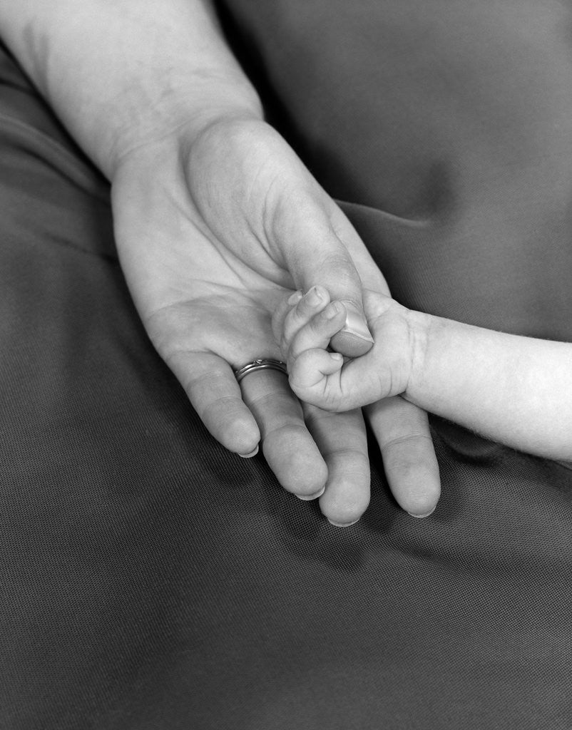 Detail of 1950s close-up of baby holding mother's thumb by Anonymous