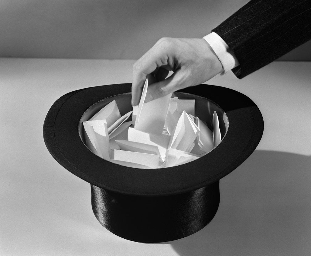 Detail of 1930s man's hand in top hat full of paper pulling name out of hat by Corbis