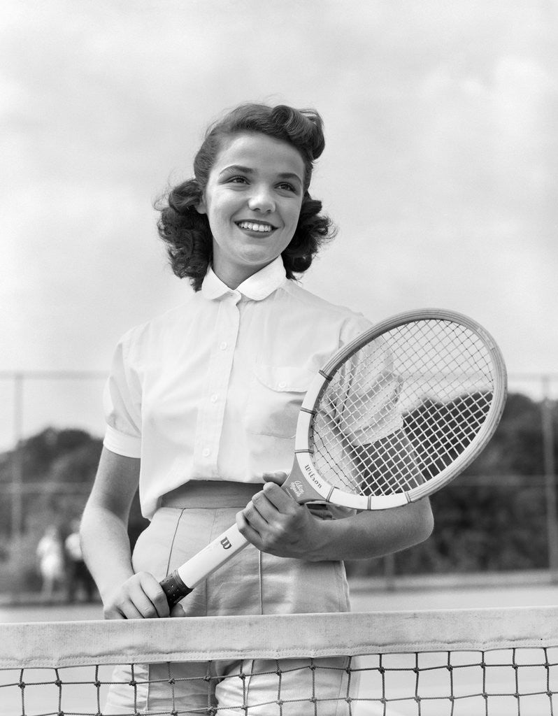 Detail of 1950s 1940s woman posing with tennis racket on tennis court near net by Anonymous