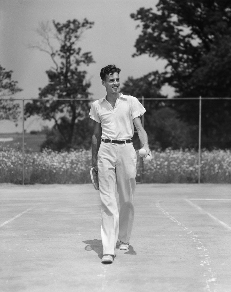 Detail of 1930s man walking across tennis court holding tennis racket & balls by Anonymous