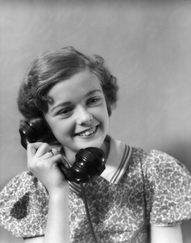 Detail of 1930s teen girl smiling brunette print dress talking on telephone by Anonymous