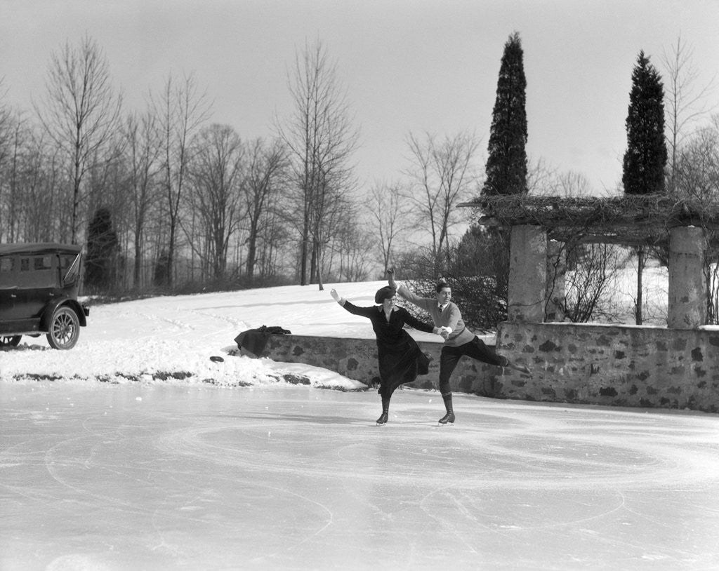 Detail of 1920s couple man woman ice skating on outdoor rink with car nearby skating side by side by Anonymous