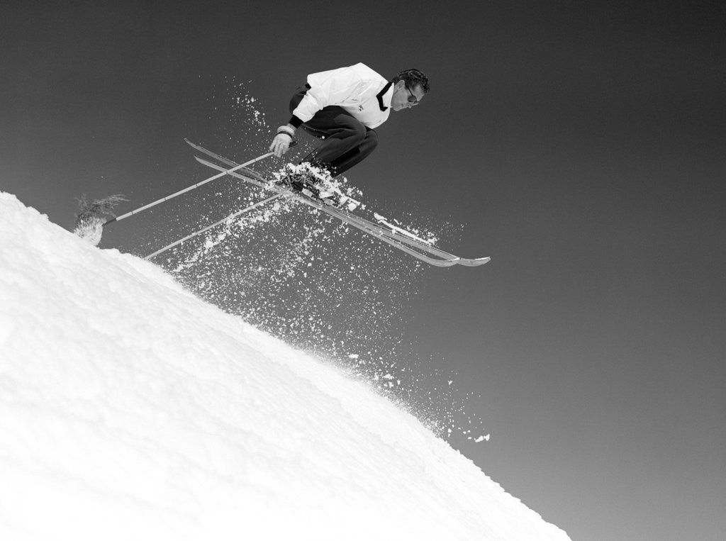 Detail of 1950s man skier skiing down slope jumping into air by Corbis