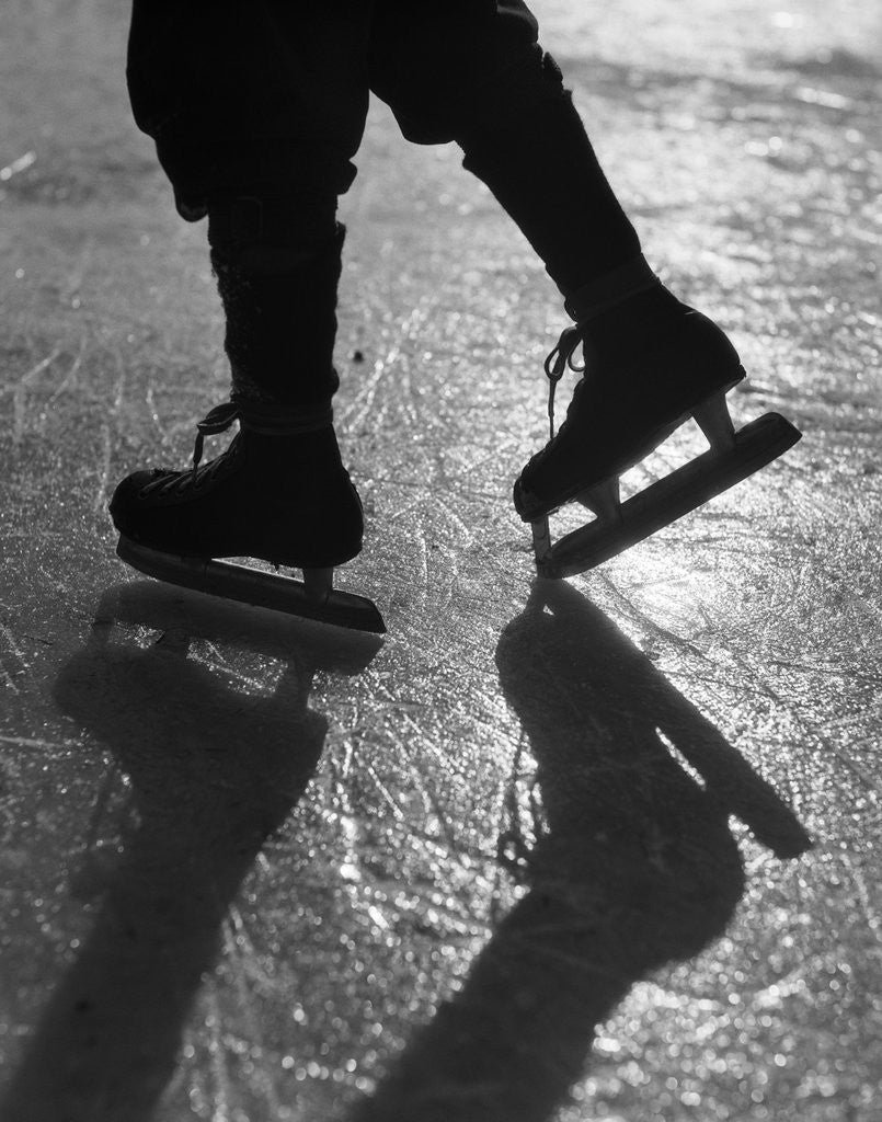 Detail of 1930s silhouette figure shown from knees down wearing ice skates skating in ice sun glare by Anonymous