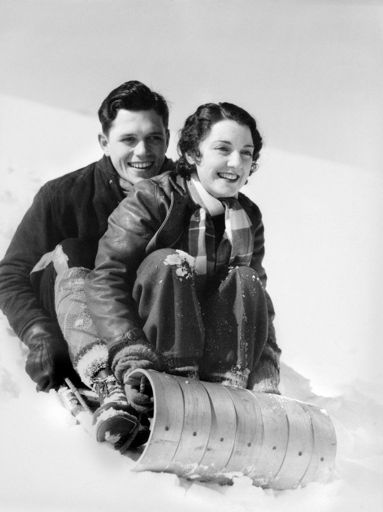 Detail of 1920s 1930s smiling couple man and woman on toboggan in winter by Corbis