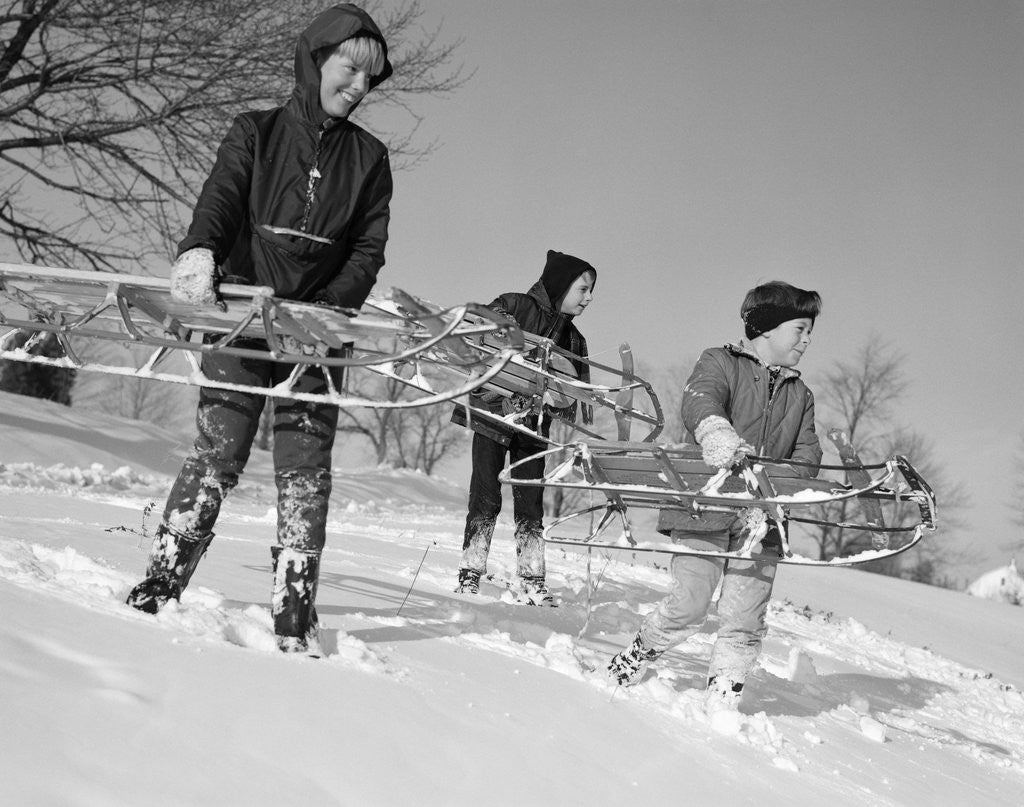 Detail of 1960s three boys holding sleds looking downhill by Corbis