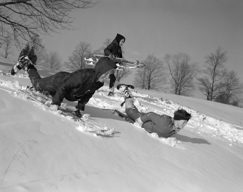 Detail of 1960s 3 boys sledding running down hill in winter snow by Anonymous