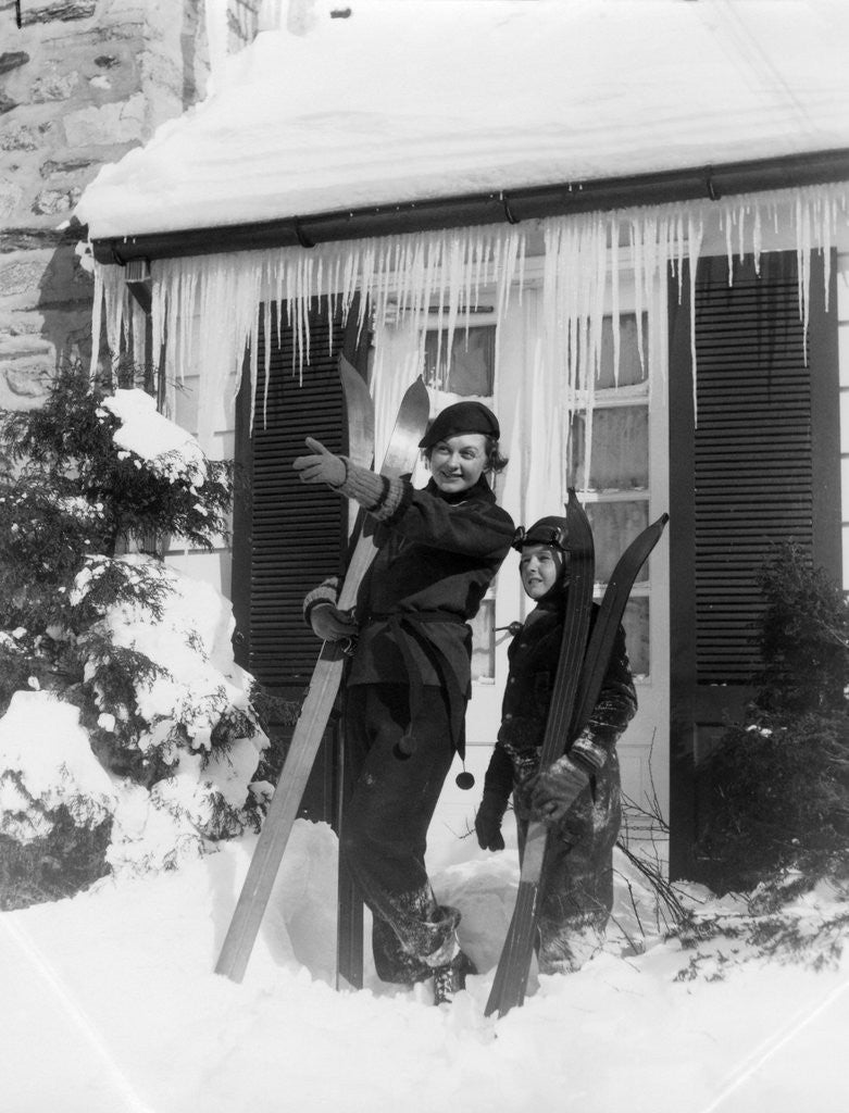 Detail of 1940s 1930s mother son standing holding skis in front of winter house with icicles by Corbis