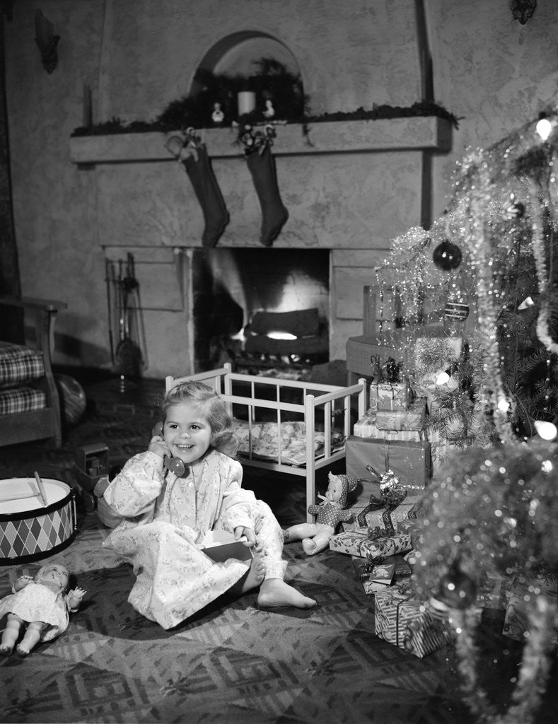 Detail of 1950s smiling little girl christmas tree talking on toy telephone by Anonymous