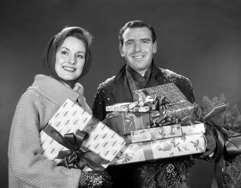 Detail of 1960s smiling couple man and woman holding wrapped christmas presents and packages by Anonymous