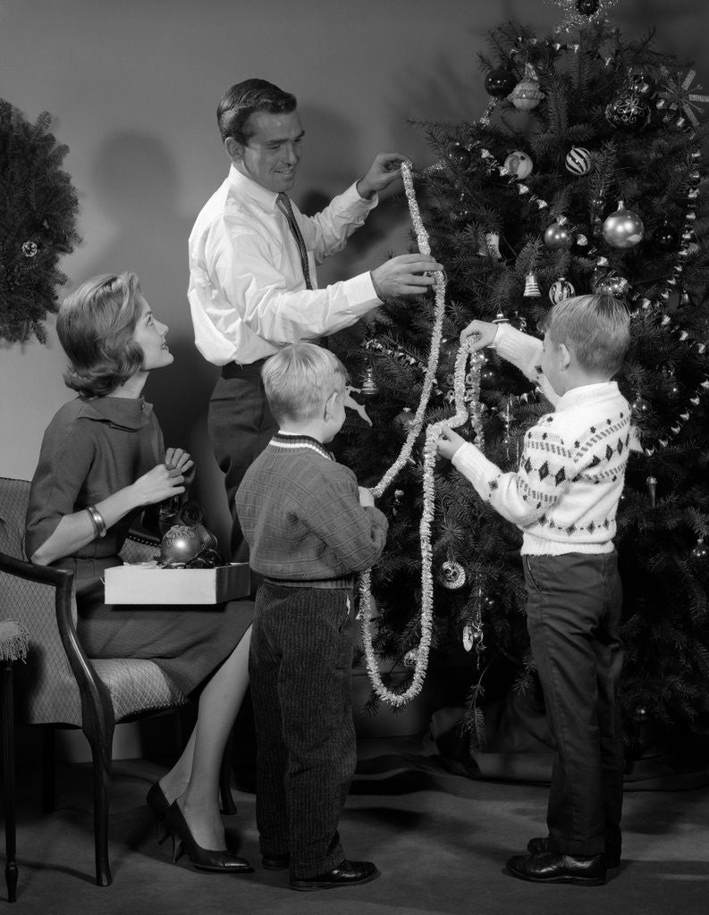 Detail of 1960s family father mother two sons trimming christmas tree with string of popcorn by Anonymous