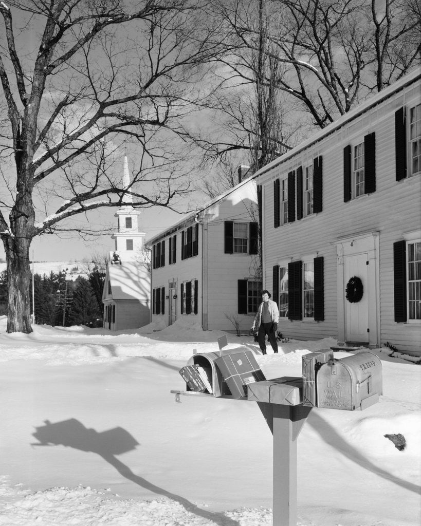 Detail of 1960s woman walking to rural mailbox in front of home in snow piled with christmas packages by Anonymous
