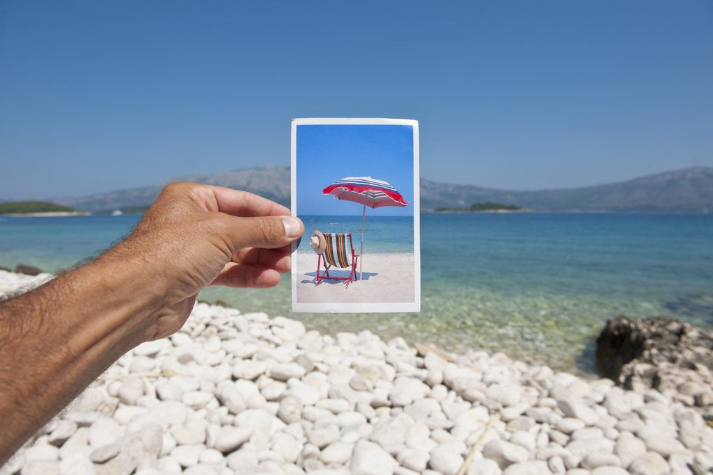Detail of Hand holding photograph depicting deck chair and sunshade, Lumbarda, Korcula island, Croatia by Anonymous