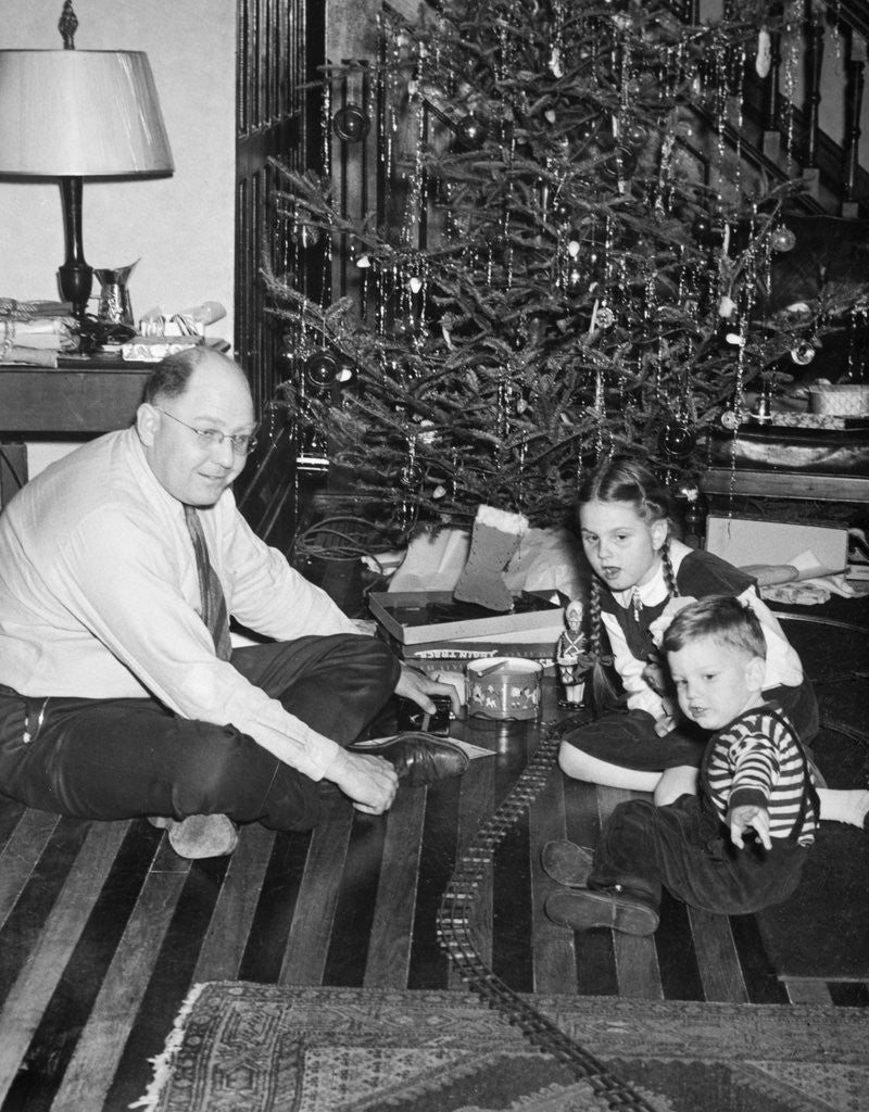 Detail of Father with daughter and son in front of Christmas tree, ca. 1950 by Corbis