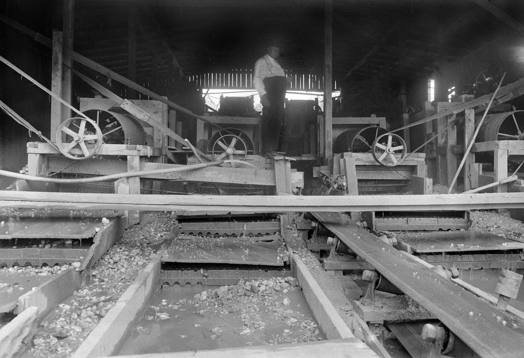 Detail of A worker stands over a rock or gravel processing facility, ca. 1910 by Anonymous