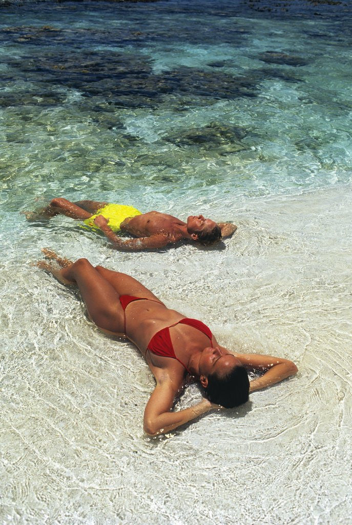 Detail of 1990s Couple Sunbathing In Shallow Water At The Ocean's Edge by Anonymous