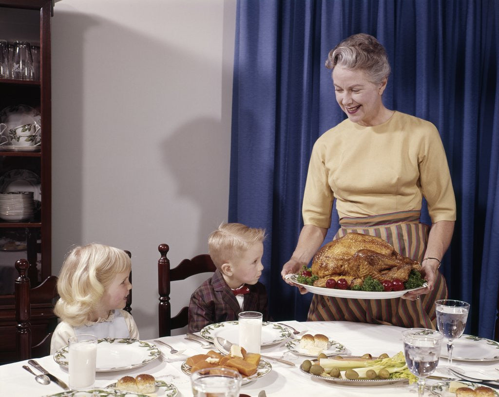 Detail of 1960s Grandmother Presenting Roasted Turkey To Children At Dining Room Table by Anonymous