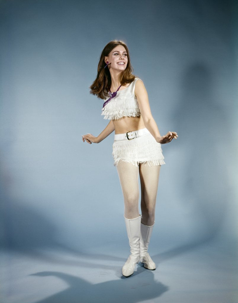 Detail of 1970s Smiling Young Woman Dancing Wearing White Fringed Top Miniskirt And Go-go Boots by Corbis
